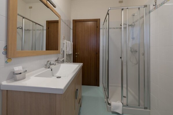 A bathroom with a sink, mirror, and shower.