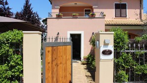 A two-story building with a wooden gate, a balcony with potted plants, and a sign with the name "ELLEBI". - Ellebì B&B (Mosciano Sant'Angelo)