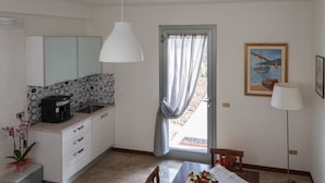 A compact kitchen with a coffee maker, a dining table with a vase of flowers, and a painting on the wall. - Ellebì B&B (Mosciano Sant'Angelo)