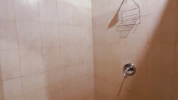 Um pequeno banheiro com box revestido em azulejo, teto azul e piso em azulejo.