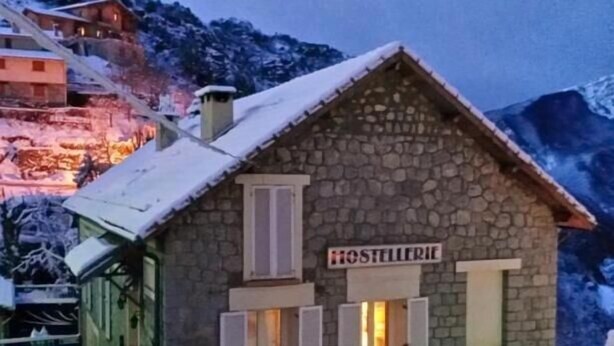 Un edificio de piedra con un letrero que dice "Hostellerie" y un letrero para un restaurante.
