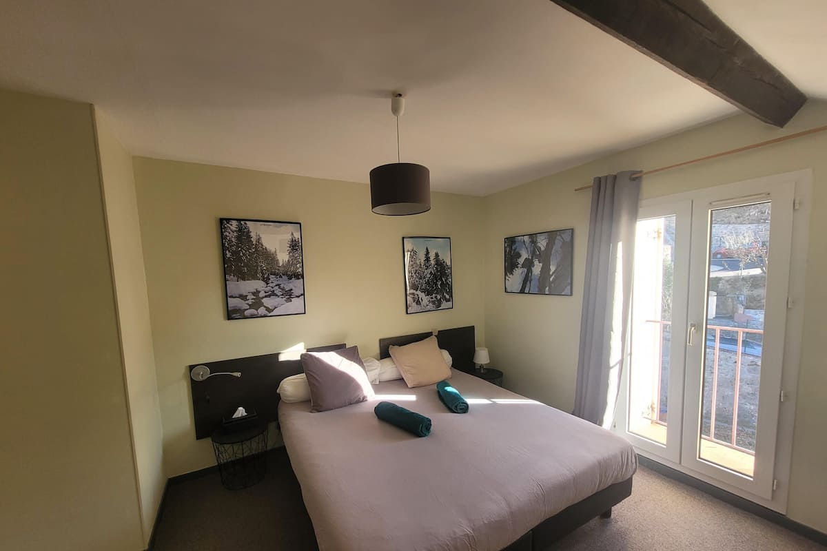 A hotel room with a large bed, two side tables, and a window with a view of the outside.