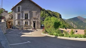 Un edificio de piedra con un letrero que dice "HOTELERIE" y vistas de montañas al fondo.