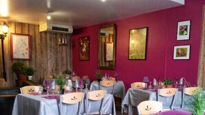 Un restaurante con mesas dispuestas para comer, sillas y plantas en macetas.