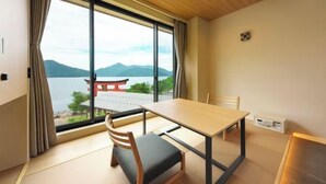 Ein Zimmer mit Holztisch und Stühlen, großen Fenstern mit Bergblick und einem traditionellen Tor.