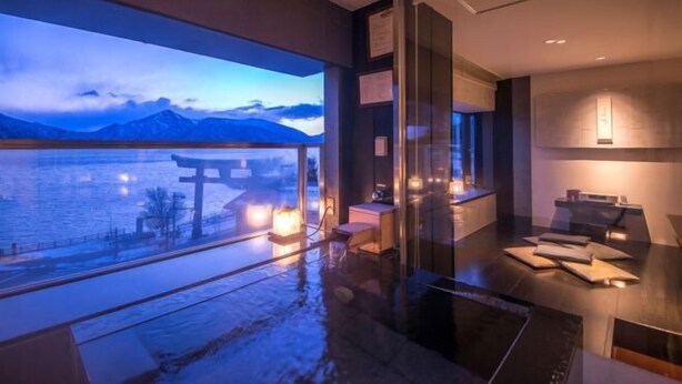 A modern hotel room with a large window overlooking a body of water and mountains.