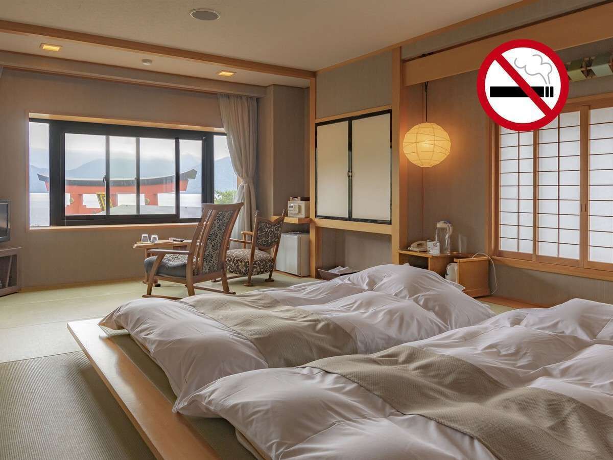 A hotel room with a bed, a desk, a chair, and a view of a traditional building.