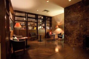 Une bibliothèque avec des étagères, des fauteuils confortables et des tables.