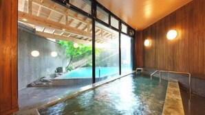 A spa area with a hot tub, wooden walls, and large windows overlooking a garden.