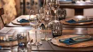 Una mesa de comedor dispuesta con copas de vino, platos y cubiertos.