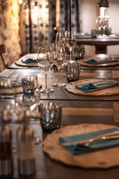 Una mesa de comedor dispuesta con copas de vino, platos y cubiertos.