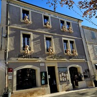 Un edificio con cartel de hotel y restaurante. Se ven ventanas con osos de peluche en el alféizar.