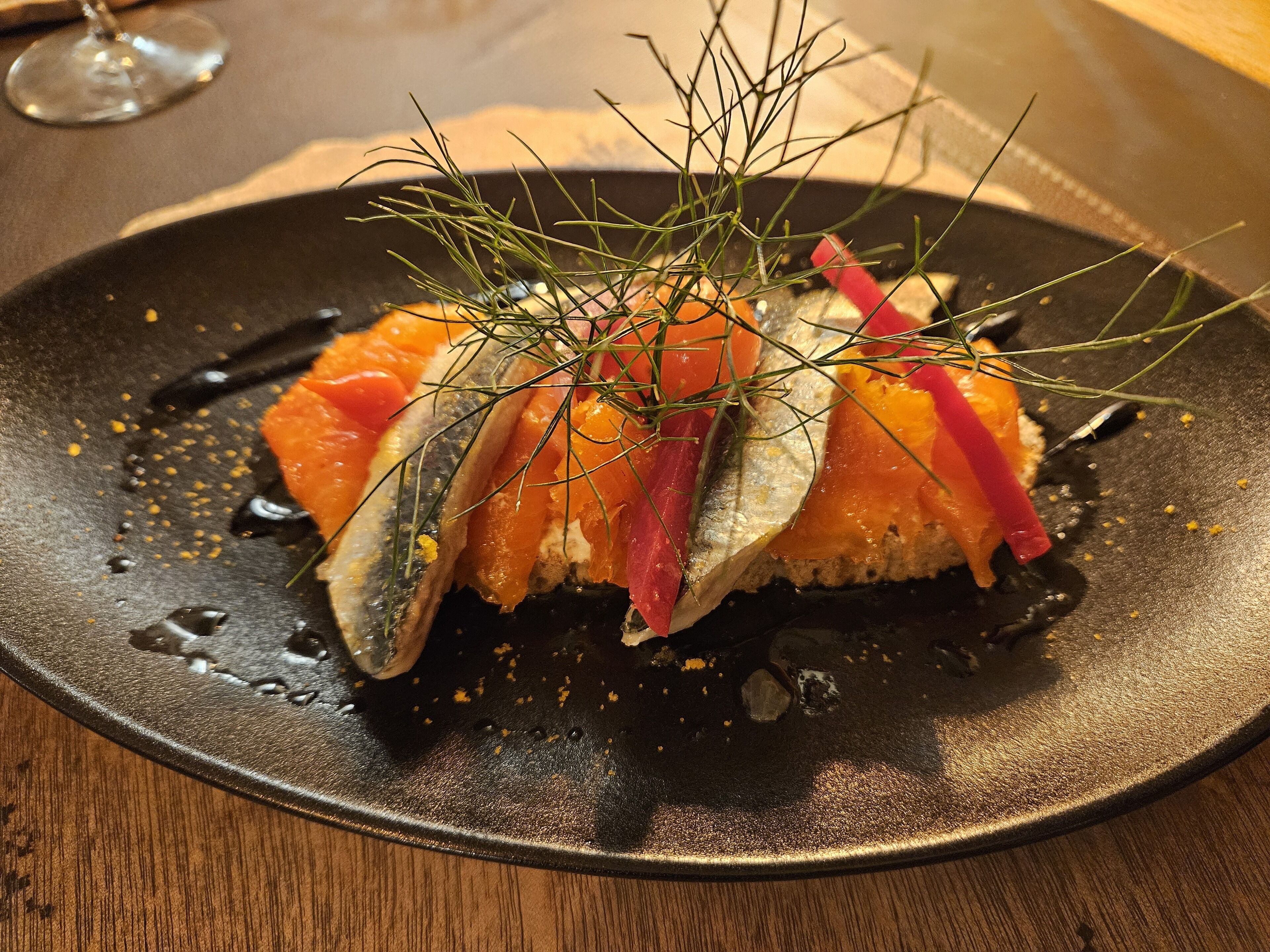 A dish with salmon and fish on a black plate.