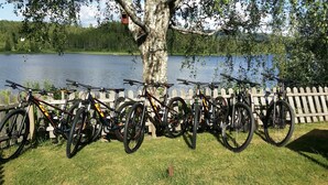 Une rangée de vélos est garée près d’une clôture en bois, non loin d’un lac.