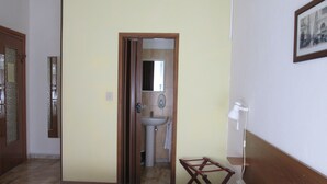 A hallway with a wooden door, a mirror, a sink, and a small table with a lamp.