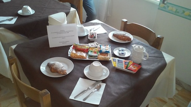 A breakfast setting with a variety of pastries, a coffee pot, and a tray of assorted food items on a table.