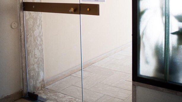 Une porte d’ascenseur fermée, avec un panneau sur le mur et un tableau de commande sur le côté gauche.