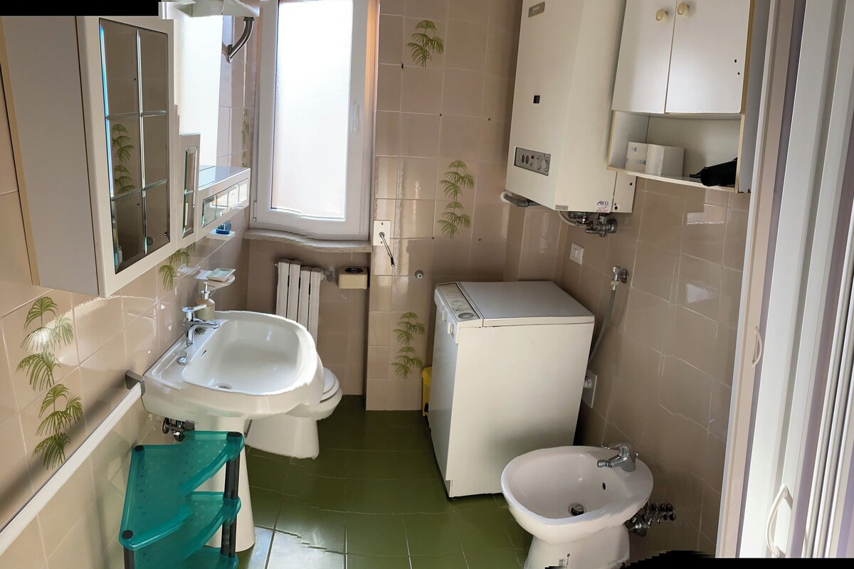 A compact bathroom with two sinks, a toilet, and a washing machine.