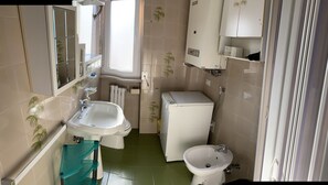 A compact bathroom with two sinks, a toilet, and a washing machine. - Casa Papapietro (Matera)