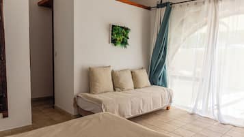Une chambre à coucher avec un lit, un canapé et une fenêtre avec des rideaux.