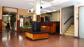 Un vestíbulo con mostrador de recepción, una escalera y una planta.