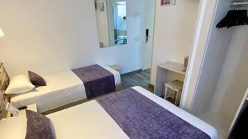 Una habitación de hotel con dos camas, un armario, un espejo y una televisión.