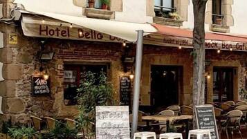 Un hotel anomenat "Hotel Bella Donna" amb terrassa exterior i un cartell que indica que està obert.