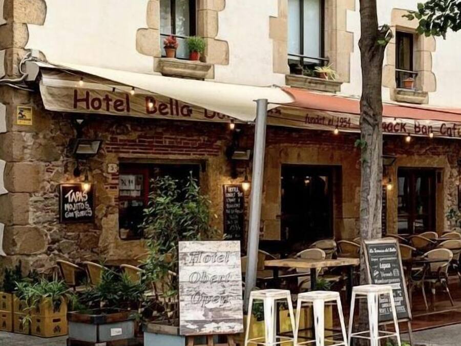 Un hotel anomenat "Hotel Bella Donna" amb terrassa exterior i un cartell que indica que està obert.