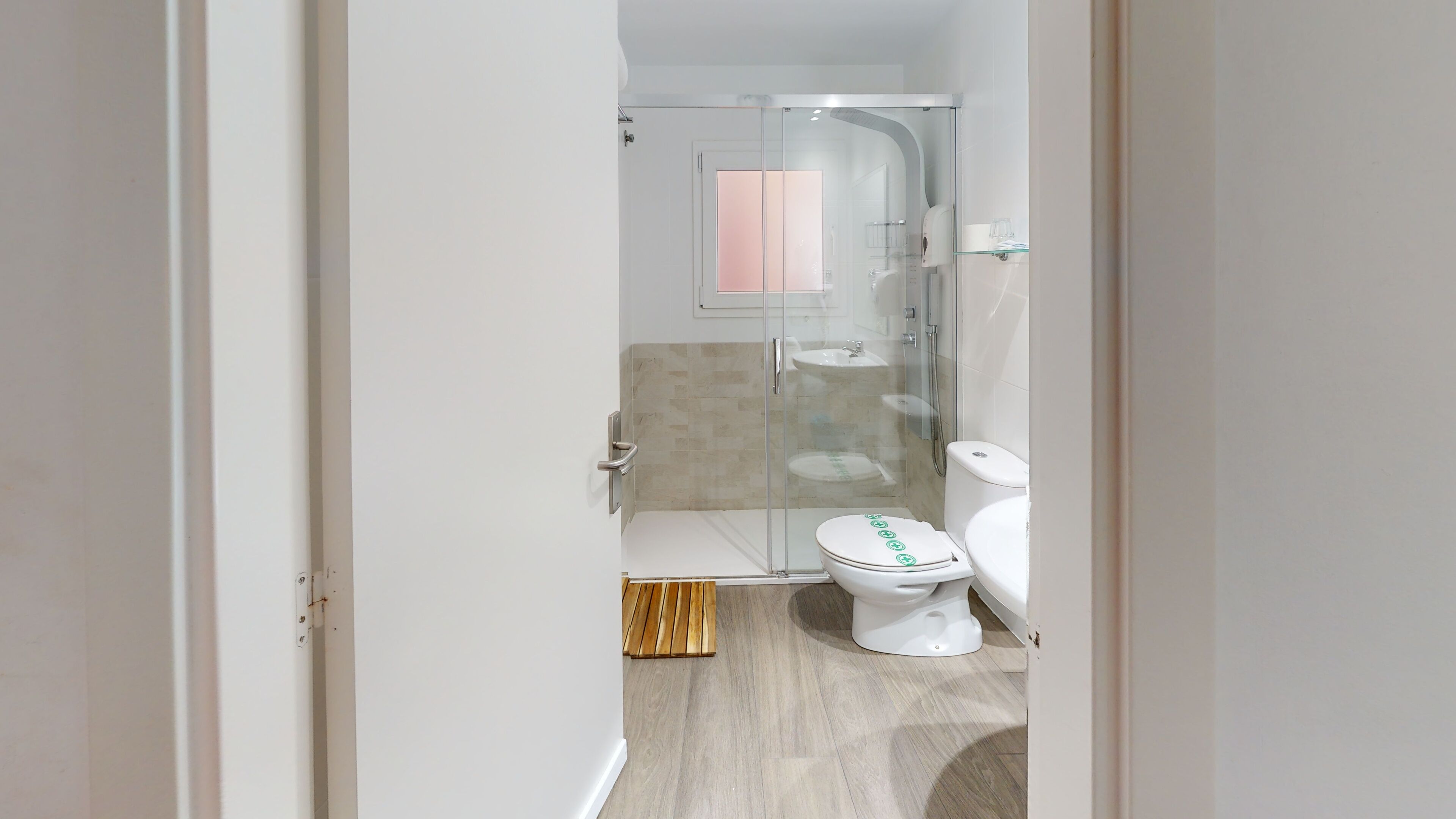 Een moderne badkamer met een douchecabine van glas, toilet en wastafel.