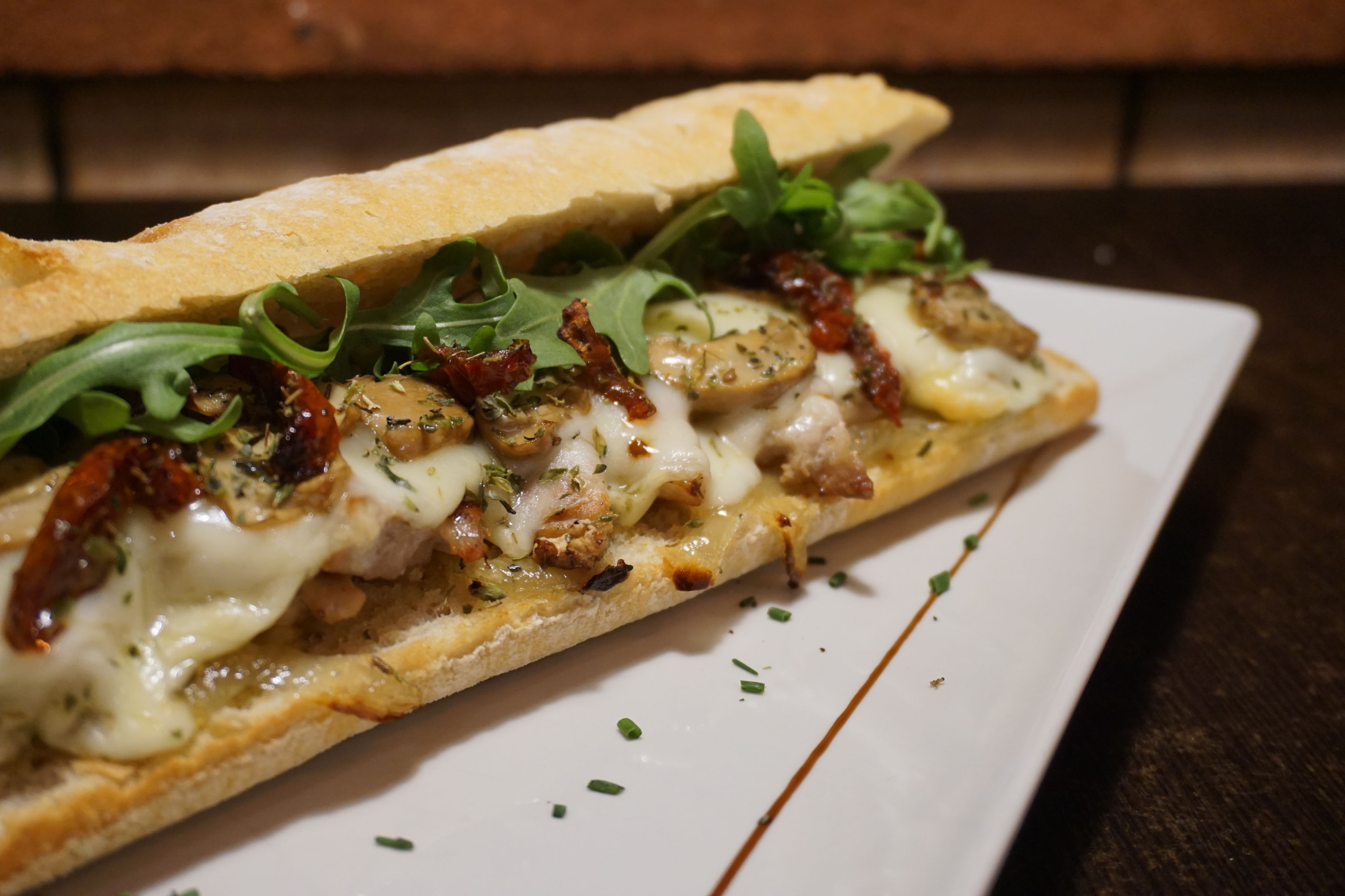 A sandwich with various toppings on a white plate.