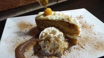 A slice of cake with whipped cream and a chocolate sauce on a white plate.