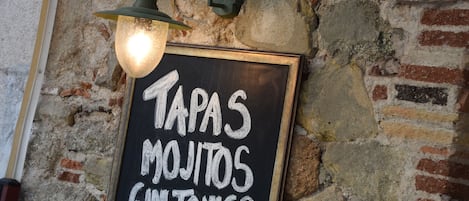 A chalkboard sign advertising tapas, mojitos, and gin tonics.