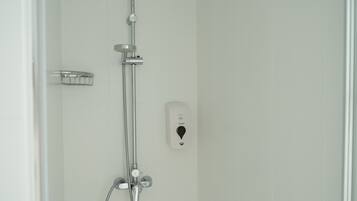 A shower with a handheld showerhead, a wall-mounted faucet, and a control panel.