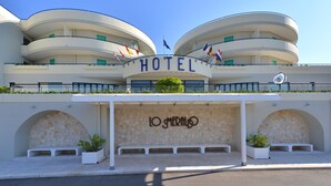 Een hotel met een gebogen gevel, meerdere balkons en een bord waarop 