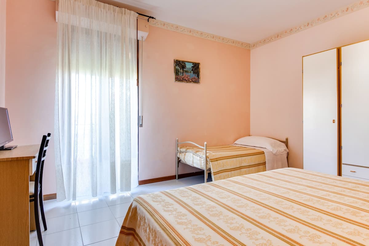 A bedroom with a bed, a desk, a chair, and a wardrobe.