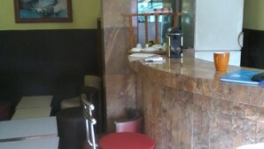 Una habitación pequeña y limpia con una única silla roja, un refrigerador blanco y un cuadro en la pared.