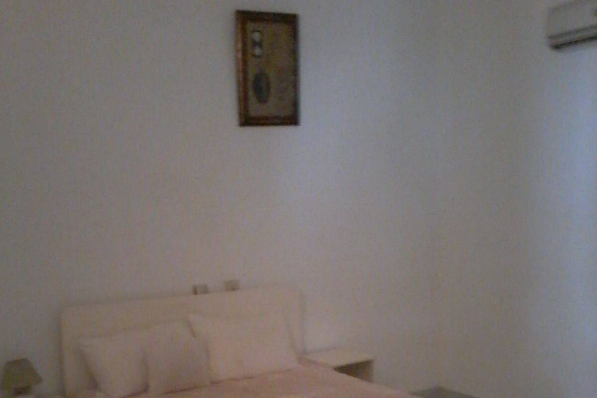 Une chambre à coucher avec un lit, une table de chevet et un tableau accroché au mur.
