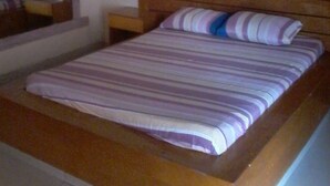 Una cama individual con cabecera de madera y colcha a rayas.