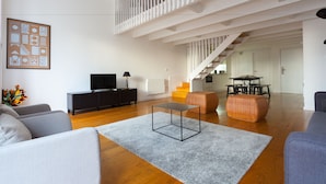 A modern living room with a staircase, a flat-screen TV, and a dining area. - City View - Santa Catarina (Porto)