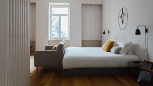 A bedroom with a bed, a chair, a nightstand, a window, and a wardrobe. - City View - Santa Catarina (Porto)