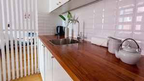 A kitchen with a wooden countertop, a stainless steel sink, a kettle, and a coffee maker. - City View - Santa Catarina (Porto)