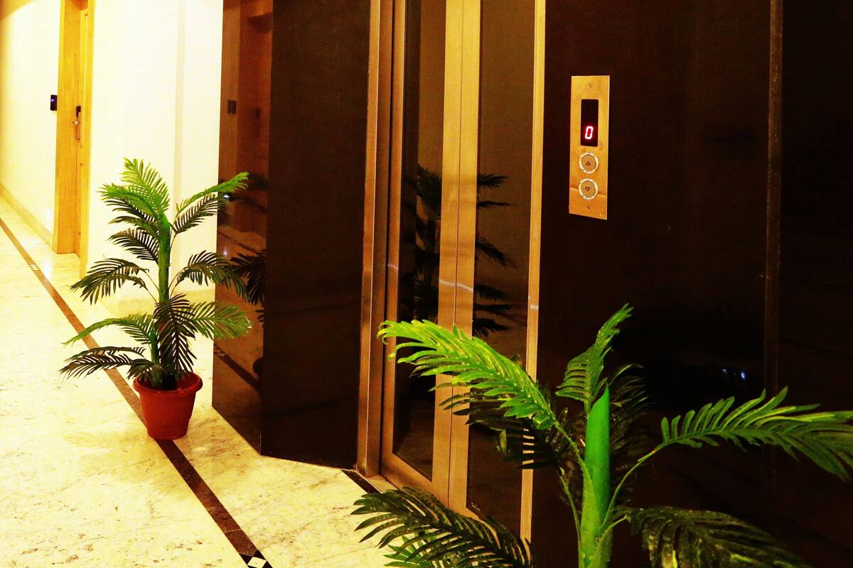 Um elevador com mostrador digital, uma planta em vaso e teto de madeira em um corredor.