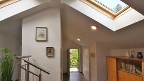 A hallway with a skylight, a staircase, and a bookshelf. - Apartments Winkler (Bad Goisern)