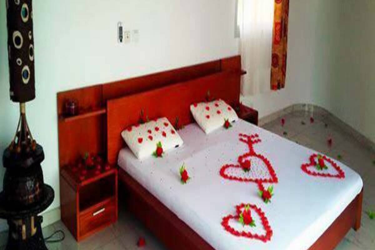 A bedroom with a wooden bed, white bedding, and red heart decorations on the bedspread.