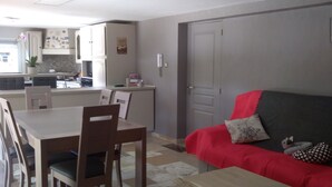 A compact living space with a dining area, kitchenette, and a red sofa with a polka dot cushion. - Chez Colombine (Chaponost)