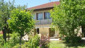 A two-story house with a balcony, surrounded by lush greenery and a well-maintained garden. - Chez Colombine (Chaponost)