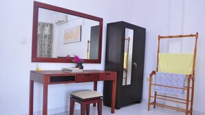Una habitación con un escritorio de madera, una silla, un armario y otra silla de madera con una tela amarilla.