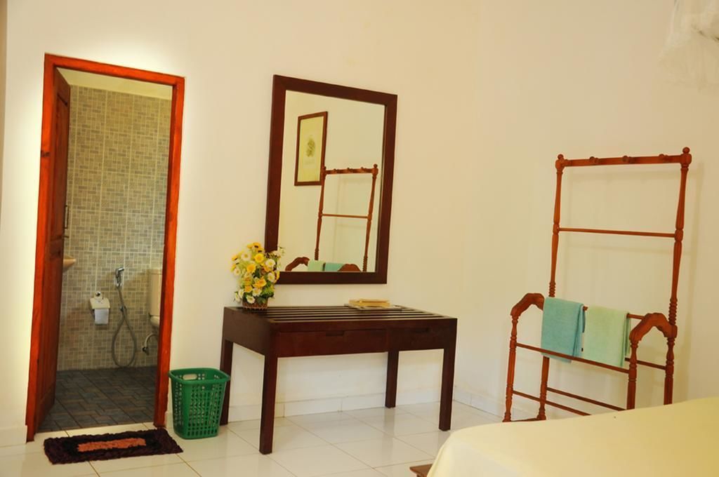 Une salle de bain avec une douche, un miroir, un banc en bois et un panier vert.