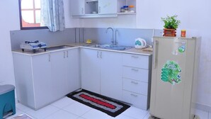 Cocina compacta con estufa a gas, pileta y heladera con un adhesivo verde.