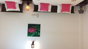 A bedroom with a bed covered in a pink blanket, white pillows, and a wall-mounted lamp. - Lo hostel (Weligama)